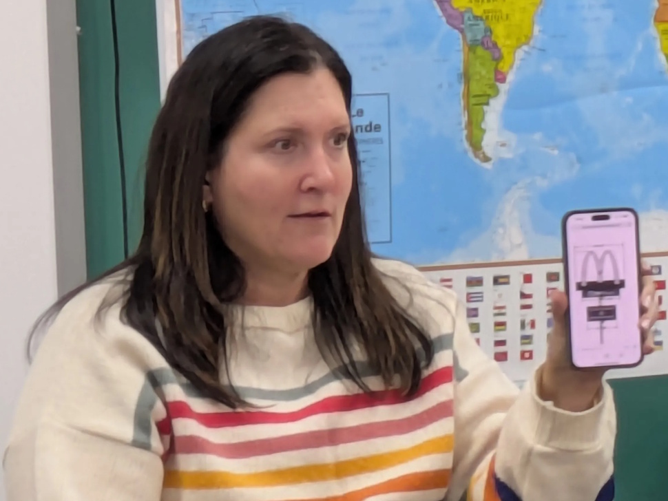 Portage la Prairie Mayor Sharilyn Knox holds up a smartphone with a recognizable fast-food logo on the screen.