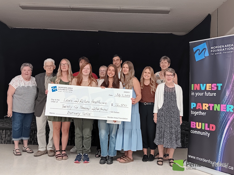 a group of people stand around a large cheque