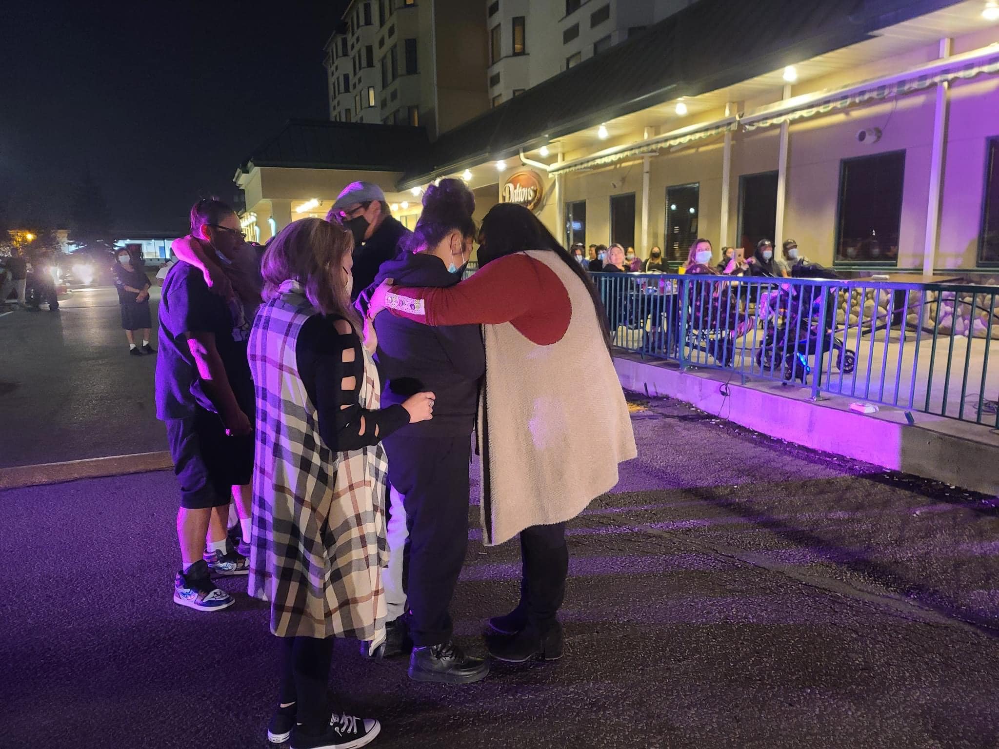 People stand in the parking lot praying with one another