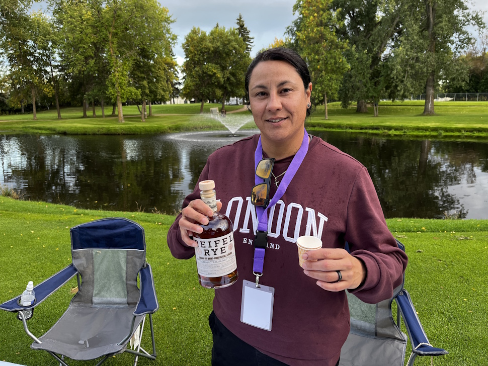 A Sip and Stroll volunteer holds up a bottle of whiskey at a tasting station inside the Portage Golf Club.