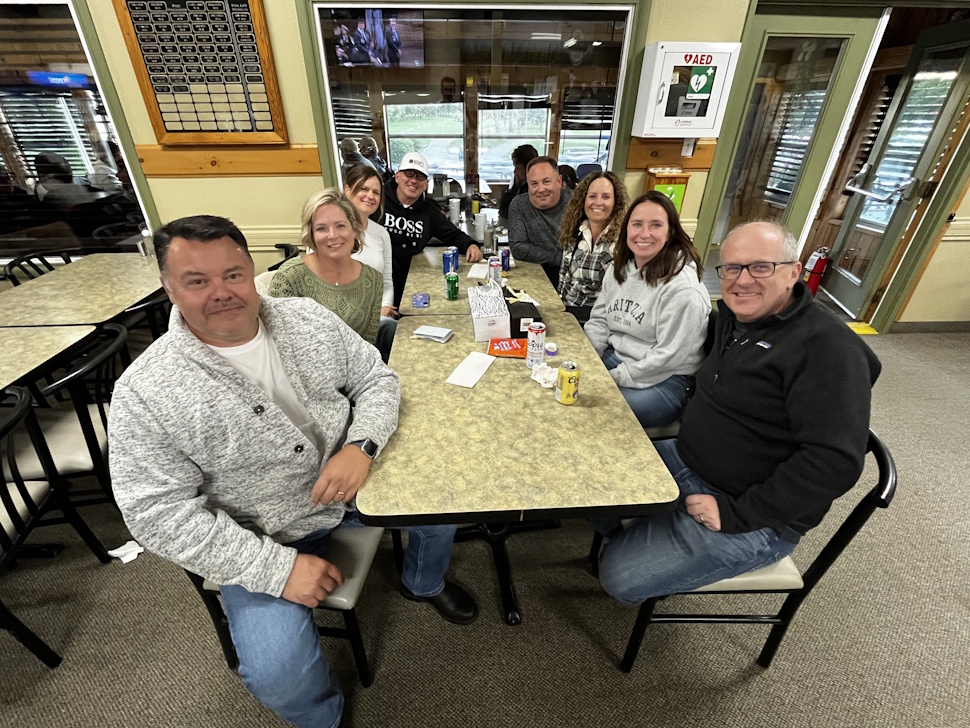 A group of Sip and Stroll participants sit at a table inside the Portage Golf Club, sharing food and drinks during the fundraiser.
