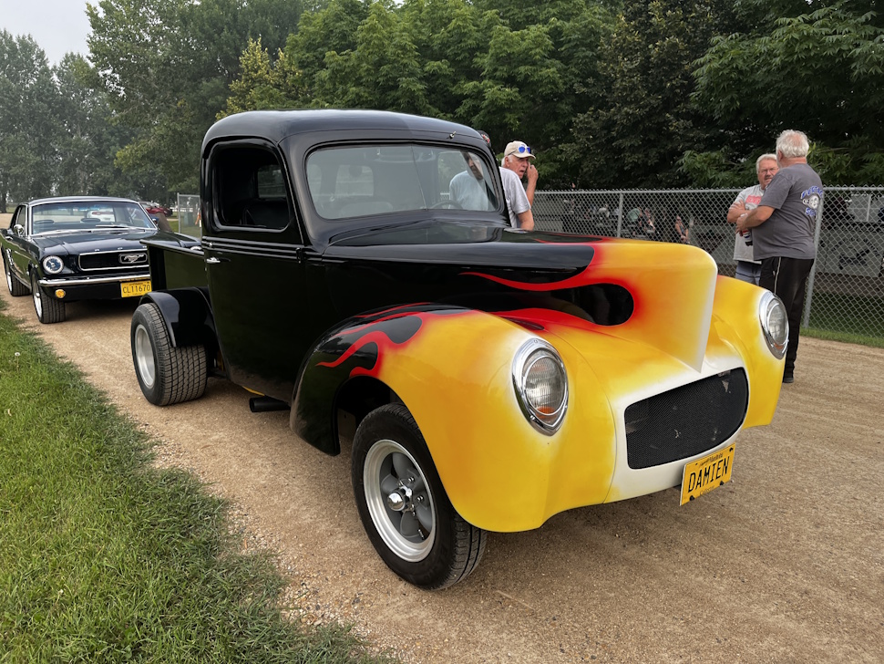 A classic truck with bright flame paint detailing is parked near the softball diamond at the Battle of the Tater Titans charity game.
