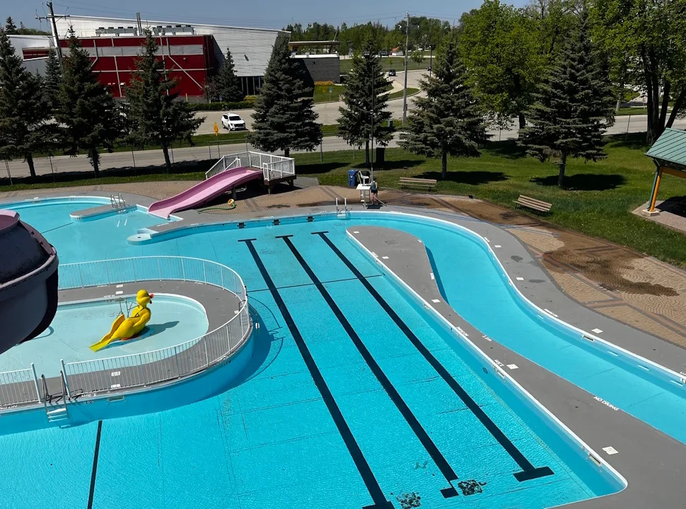 View of Splash Island water park in Portage la Prairie, showing colorful water slides and play structures with families enjoying the sunny day.