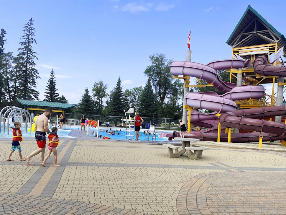 Swimmers enjoying Splash Island pool with colorful waterslides in the background.