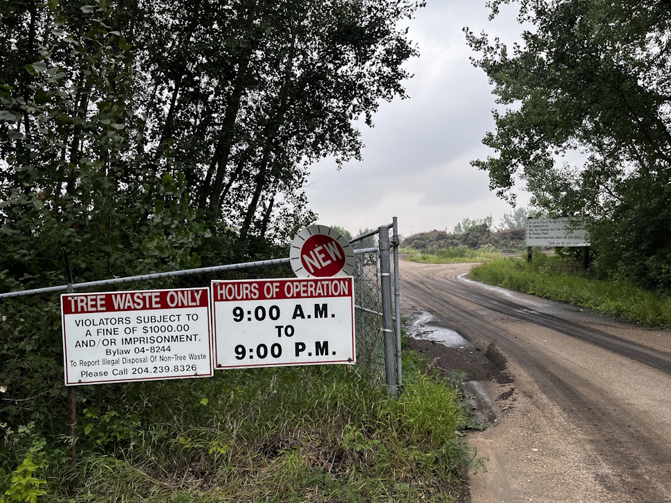 Front gate of the Portage la Prairie tree disposal site displaying posted hours of operation from 9 a.m. to 9 p.m.