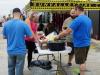 people stand around a table with food on it 