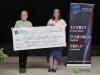 two women stand behind a giant cheque